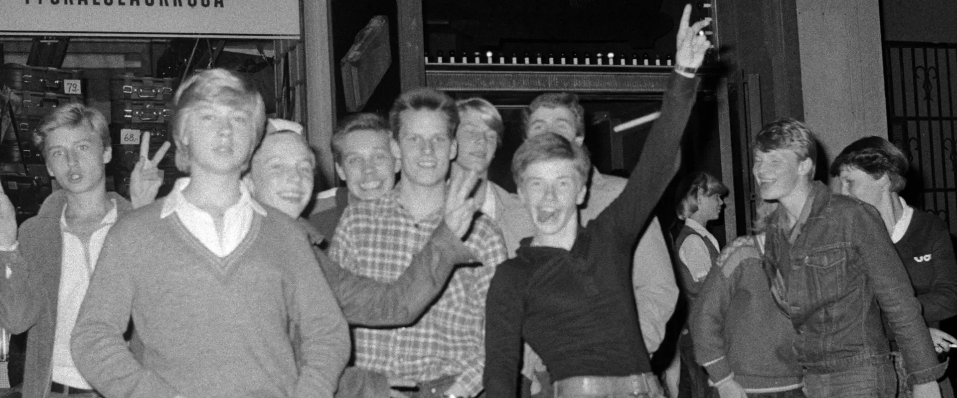 Joukko nuoria poseeraa valokuvaajalle Frisco Disco -tanssiravintolan edustalla vuonna 1978.  Kaikki ovat pukeutuneet farkkuihin, osa niin sanotun fiftarityylin mukaisesti.