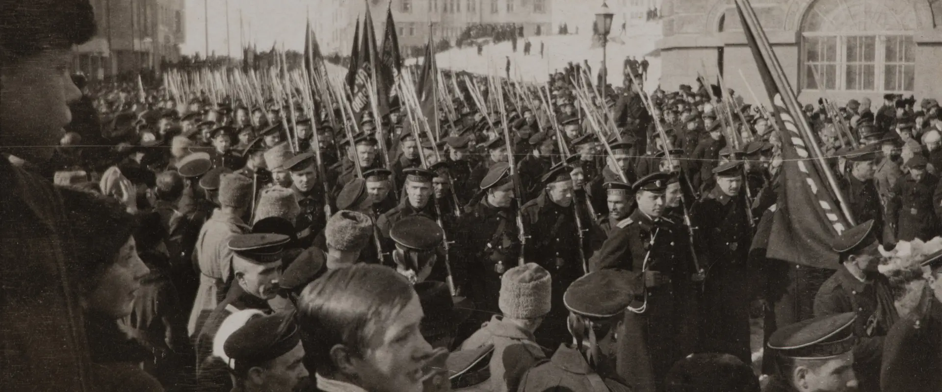 Venäläiset sotilaat juhlivat kulkueessa maaliskuun vallankumousta vuonna 1917. Kulkue on täynnä univormupukuisia miehiä, jotka kantavat lippuja.