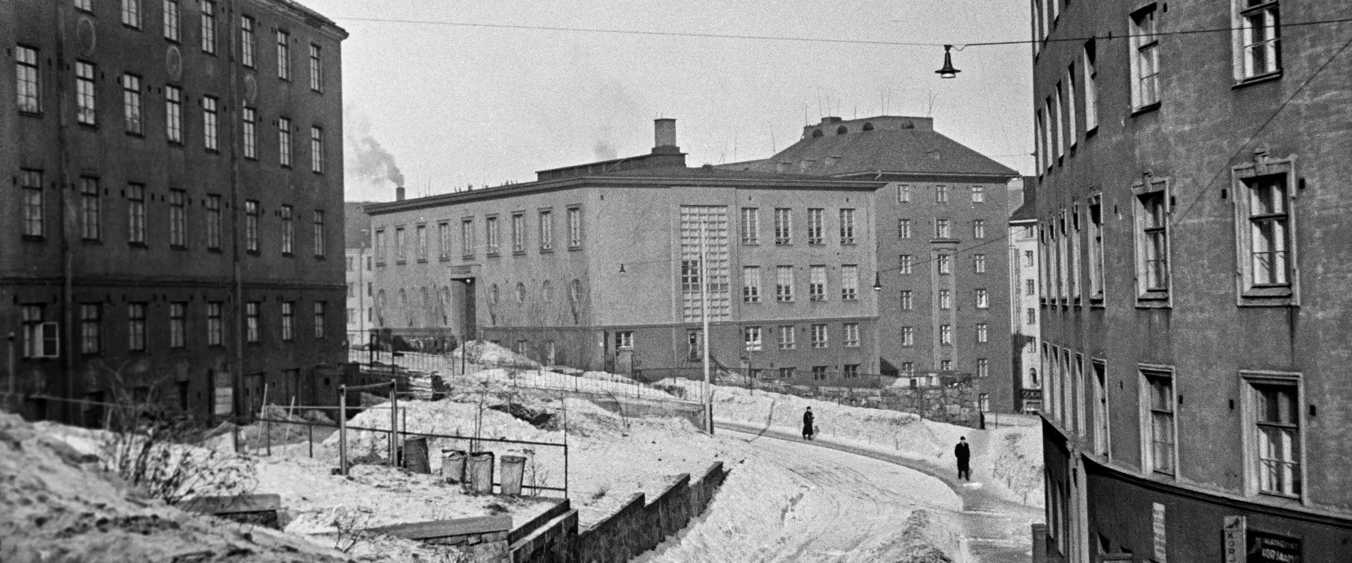 Flervåningshus och människor som går på en snöig gata.