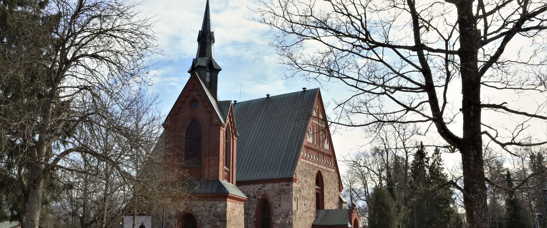 Fotografi av medeltida stenkyrka omgiven av smältande snö