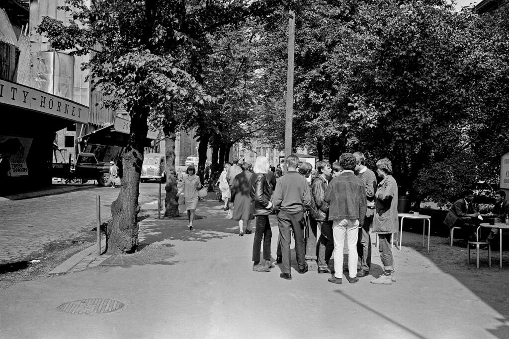 Nuoria kokoontuneena Keskuskadulle Ateneumin puistikkoon vuonna 1966. Vasemmalla näkyvän työmaa-aidan takana rakennetaan Makkarataloa. Ateneumin puistikkoa pienennettiin, kun Keskuskatua levennettiin, jotta autot pääsivät ajamaan Makkaratalon pysäköintitasanteelle ja sieltä pois. Kuvaaja: Helsingin kaupunginmuseo / Constantin Grünberg