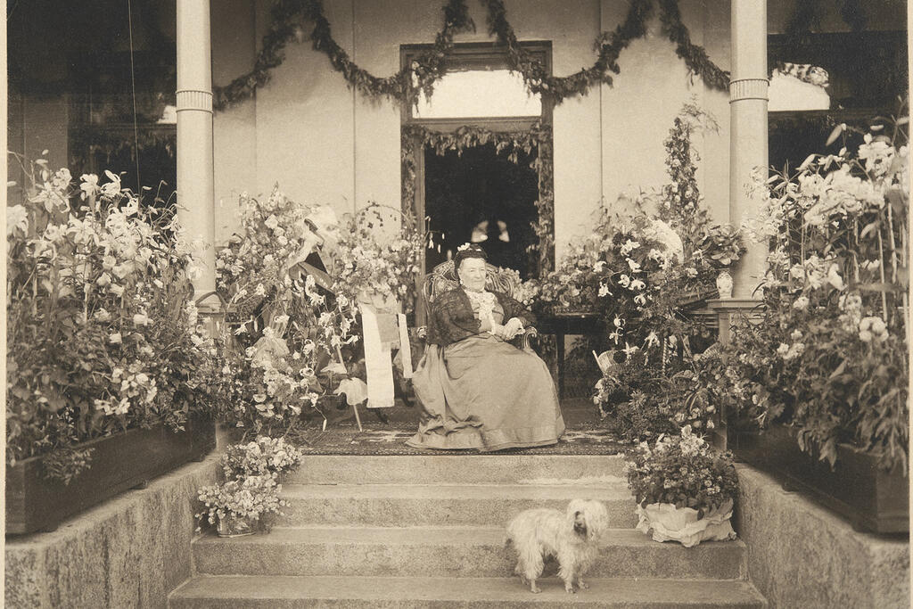 Aurora Karamzin koirineen 90-vuotispäivänään 3.8.1898 Hakasalmen huvilan terassilla onnittelukukkien keskellä. Kuvaaja: Museovirasto / K. E. Ståhlberg