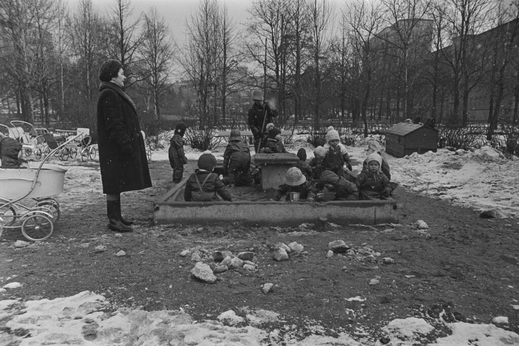 Sandlådslekar i slaskväder under parktantens vakande öga i Topeliusparken ca 1969. Foto: Helsingfors stadsmuseum / Simo Rista