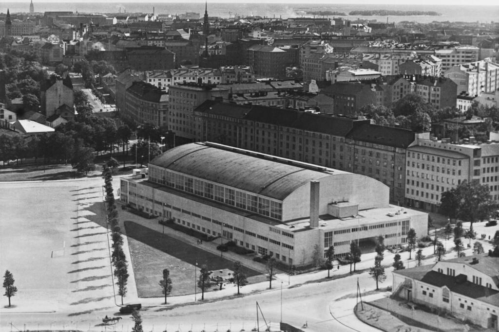 Mässhallen A som syns på bilden stod färdig år 1935. Nederst till höger står Hippodromen (en hästidrottsarena) som revs år 1949. På dess plats restes Mässhallen B år 1950. Nuförtiden är byggnaderna kända som Sporthallen. Bilden är från år 1938. Foto: Helsingfors stadsmuseum