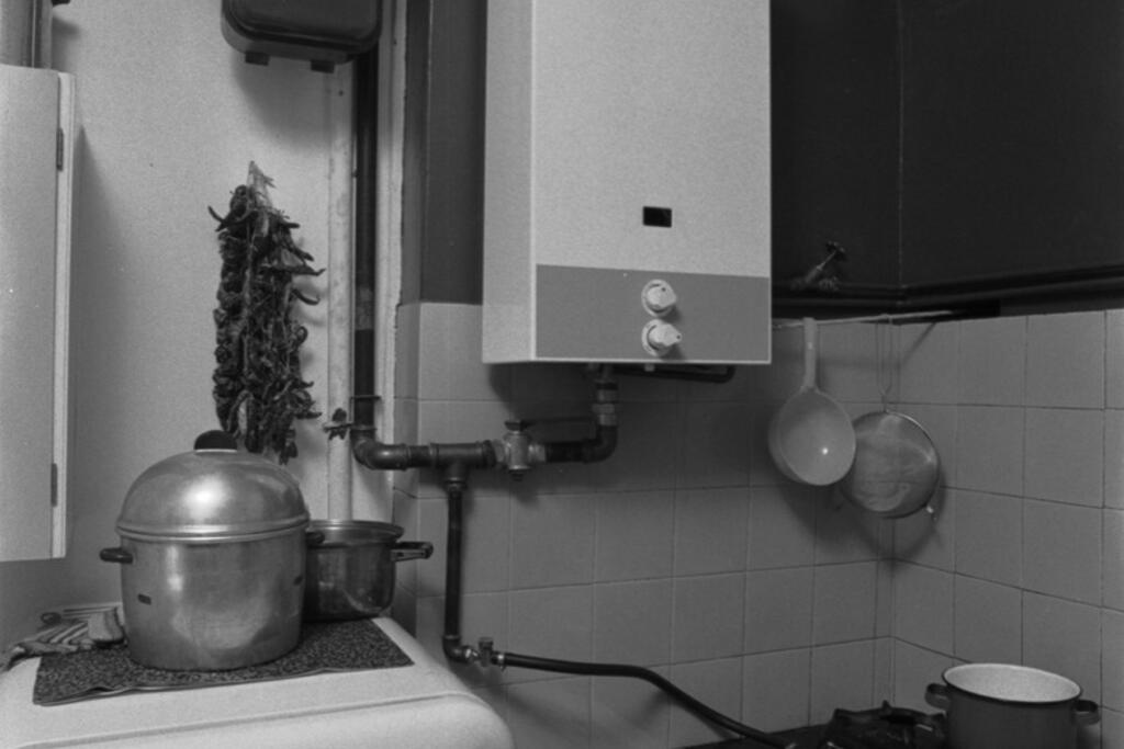Kaasu ja sähkö helpottivat arkea. Vallilalaisessa keittiössä vuonna 1973 on kaasukäyttöinen lämminvesivaraaja ja liesi, jotka on kytketty kaasun käyttöä seuraavaan kaasumittariin. Sähkökäyttöiset jääkaapit ja pakastimet korvasivat kylmäkellarit, seiniin upotetut viilennyskaapit ja kiertävät jäänmyyntikärryt. Kuvaaja: Eeva Rista / Helsingin kaupunginmuseo