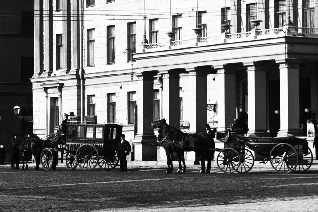 Hästfordon framför Societetshuset,alltså nuvarande stadshuset, Norra Esplanaden 11, 13. Till vänster hotellets hästdiligens och till höger en snabbkusk.  Foto: Helsingfors stadsmuseum / Daniel Nyblin