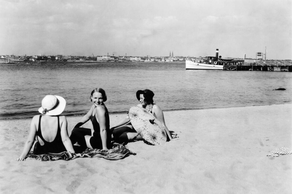 Sommarfirare på stranden på Rönnskär i början av 1930-talet. Vid bryggan syns ett ångfartyg. Foto: Helsingfors stadsmuseum / Fred Runeberg