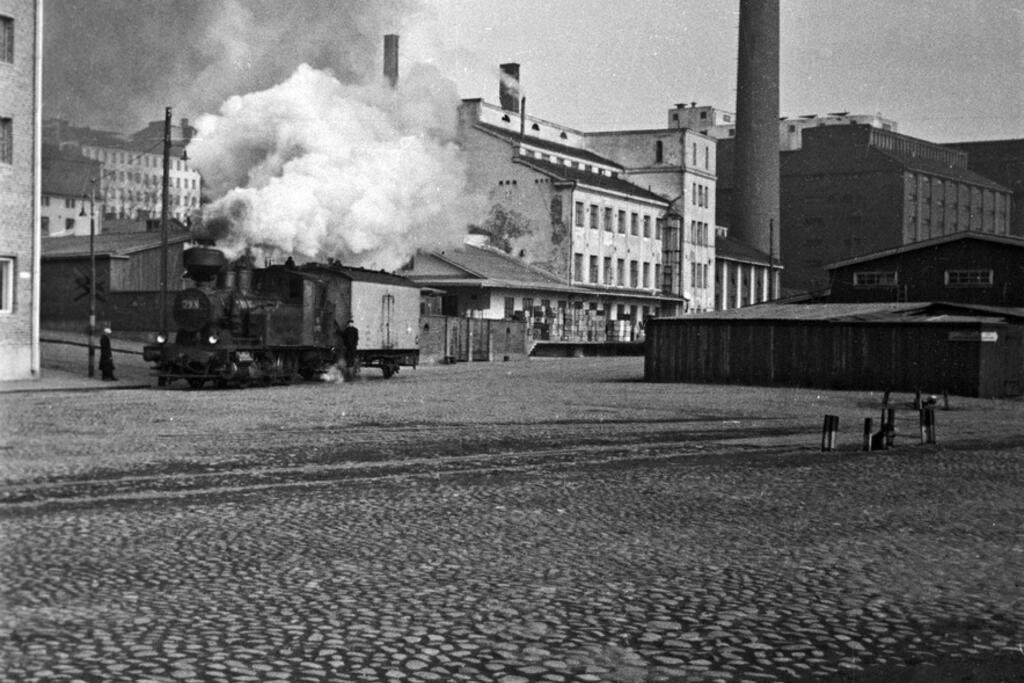 ”En bagge” eller ett jourhavande lok i korsningen av Fågelviksvägen och Ekogatan. Baggen såg till att tomma tågvagnar fanns till hands där var de behövdes i Sörnäs hamn.  Foto: Helsingfors stadsmuseum / Eino Heinonen