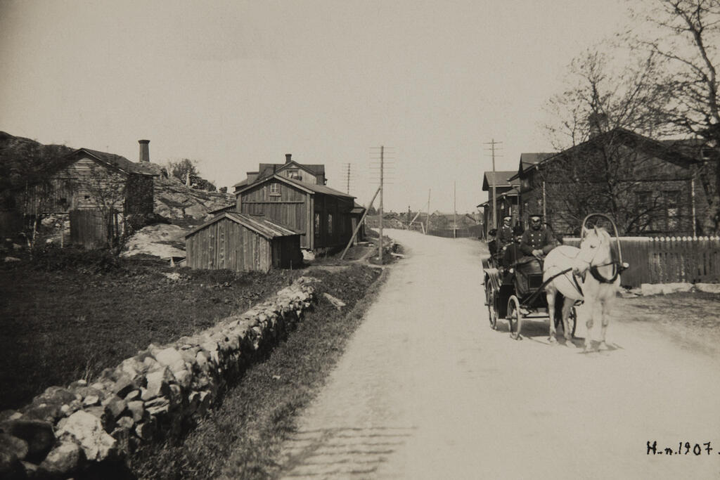 Helsingfors Fornminnesnämnd och fotografen Signe Brander på "söndagsutflykt" för att inspektera fotograferingsställen i Gammelstaden på Östra Chaussén, nuvarande Tavastvägen. Foto: Helsingfors stadsmuseum / Reinhold Hausen