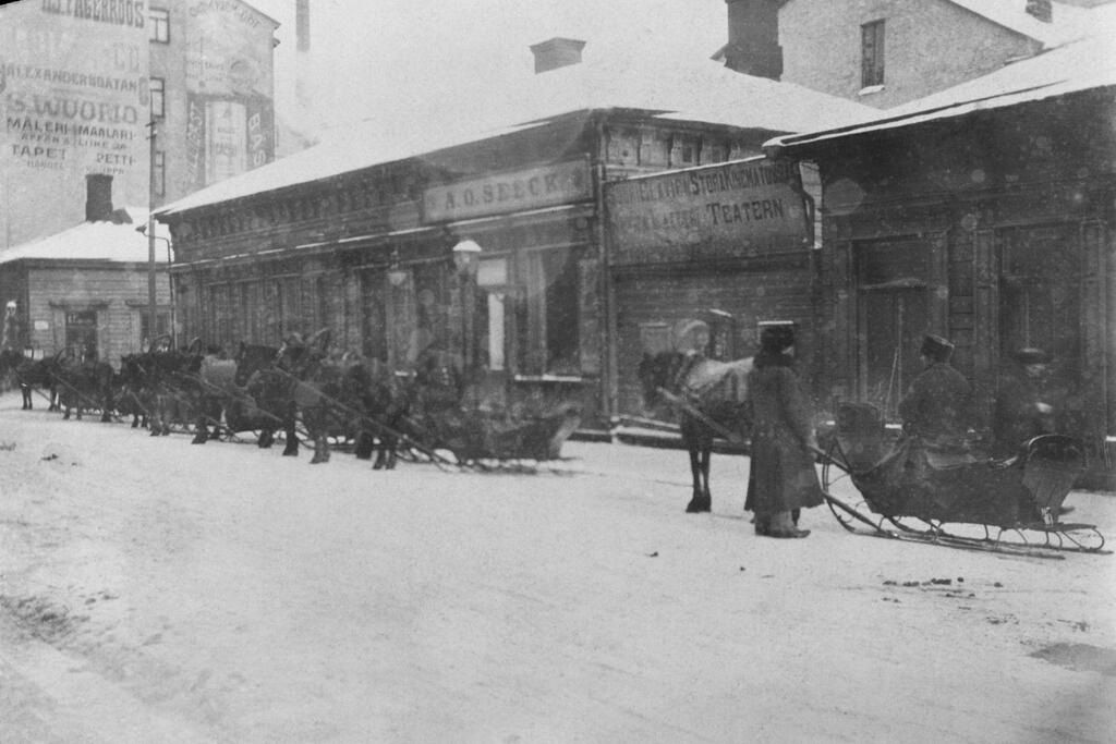 Hyrkuskar med sina hästdrivna slädar på Glogatan 3 på vintern i början av 1900-talet. Foto: Helsingfors stadsmuseum