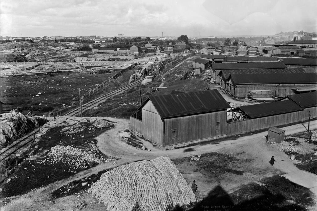 Kuva on otettu Malminkatu 40:stä koilliseen vuonna 1907. Kuvan keskellä näkyy satamarata, jonka tilalla on nykyisin Baana. Kuvaaja: Helsingin kaupunginmuseo / Signe Brander