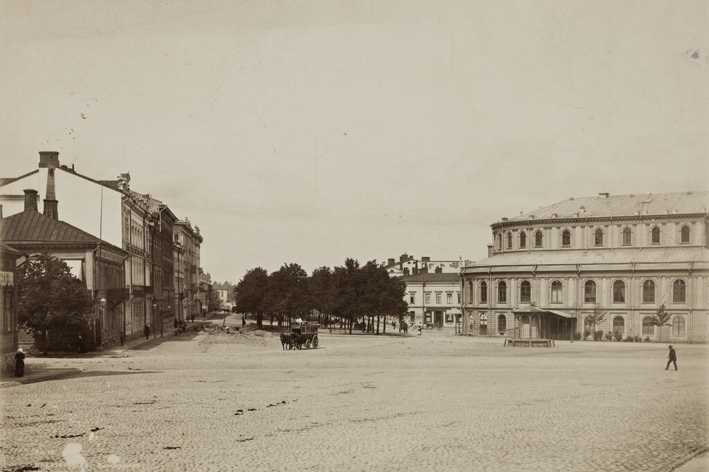 Vy från Skillnadstorget/Mellantorget mot Henriksgatan (början av det som i dag är Mannerheimvägen). Till höger på bilden syns Mellantorgets brunn och framför pågår gatuarbeten 1890.  Foto: Helsingfors stadsmuseum / Daniel Nyblin