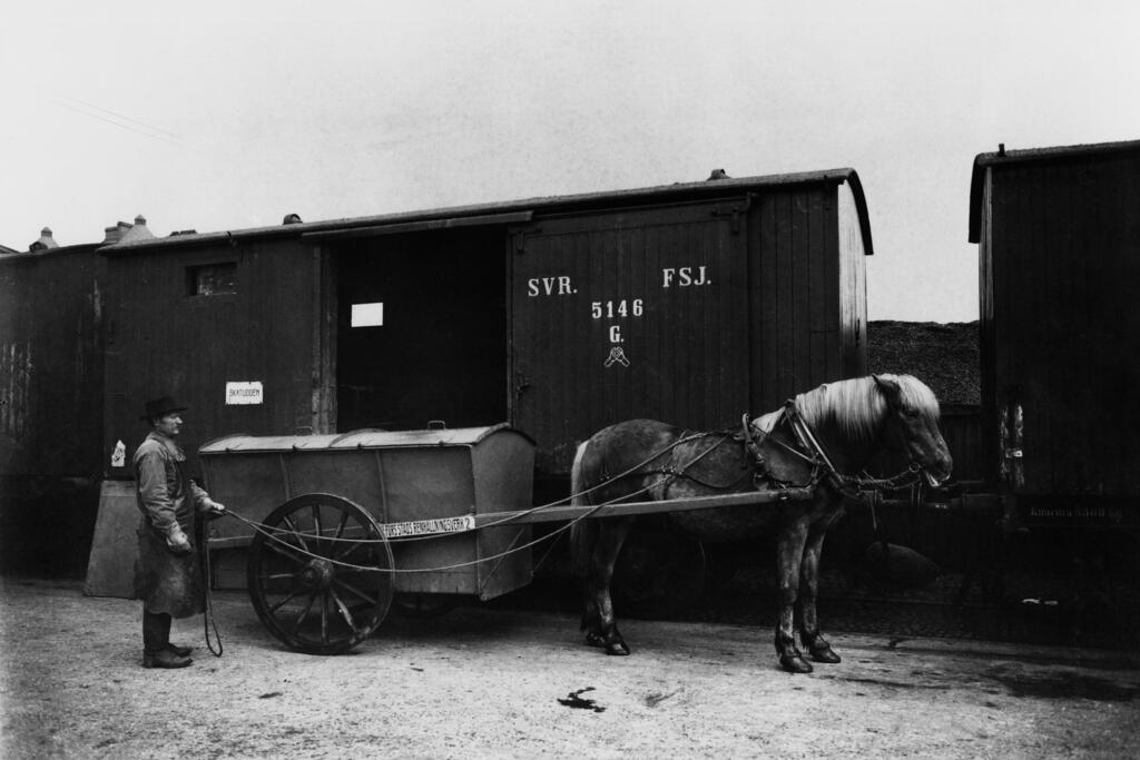 Helsingin puhtaanapitolaitoksen työntekijä lastaa kuivien roskien säiliötä junanvaunuun vuonna 1913. Kuvaaja: Helsingin kaupunginmuseo