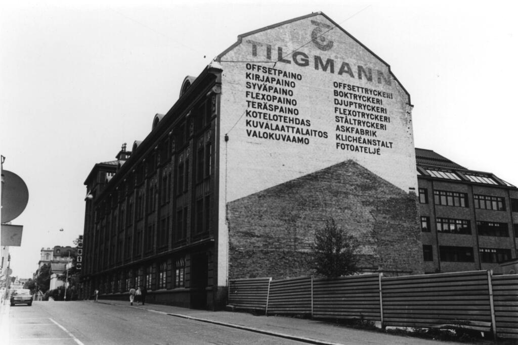 Tilgmanns tryckeri köpte 1872 den tomt som låg i hörnet av Annegatan och Lönnrotsgatan och byggde stegvis ett massivt hus där. Boktryckeriet flyttade sin verksamhet till Esbo i början av 1970-talet.