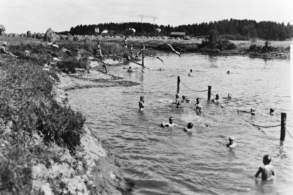 Toivolan koulukodin lapsia uimassa koulukodin uimarannalla Vantaanjoella vuonna 1937. Taustalla näkyvät heinäseipäät kertovat siitä, että maataloustyöt kuuluivat olennaisena osana koulukodin arkeen. Ajateltiin, että työnteko lapsesta asti kasvattaa punaorvot kunnon kansalaisiksi. Huiman näköinen hyppyteline taas kertoo siitä, että lapsille järjestettiin myös leikkimahdollisuuksia. Kuvaaja: Helsingin kaupunginmuseo / Tuntematon kuvaaja