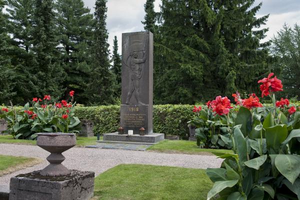 Harmaa kivipaasi pystyasennossa, johon kuvattu lippua heiluttava mies.