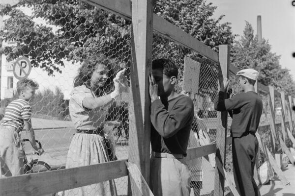 Helsingin olympialaiset 1952. Urheilijat jakavat nimikirjoituksia verkkoaidan takaa Käpylän Kisakylässä.