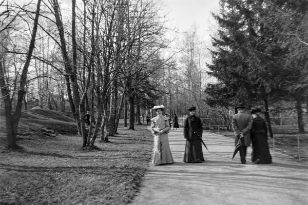 Två stiligt klädda äldre damer promenerar mot kameran på parkvägen i Brunnsparken. 