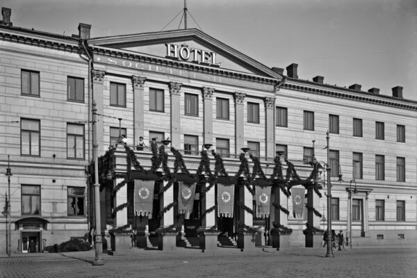 A photograph of the current Helsinki City Hall with the text “Hotel Societetshuset” on its wall.