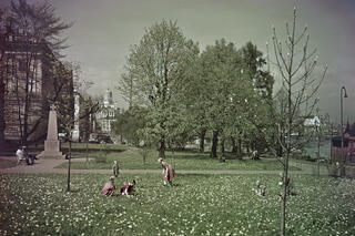 Leikkiviä lapsia Tähtitorninvuoren puistossa. Kuvan reunassa muistopaasi, jonka päällä rautaristi.