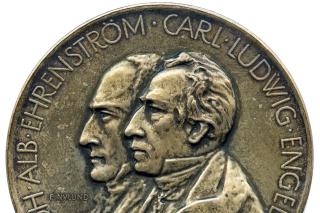Medaljen har präglats med sidoprofilen av två män. Carl Ludvig Engels profil är i mitten av medaljen och Johan Albrecht Ehrenströms profil är lite till vänster. Båda personers namn går runt medaljens kanter.