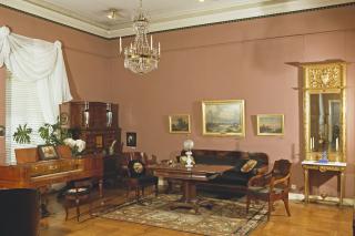 Rummet är inrett med orientaliska mattor, möbler i ädelträ, en stor väggspegel med förgylld ram samt en kristallkrona.