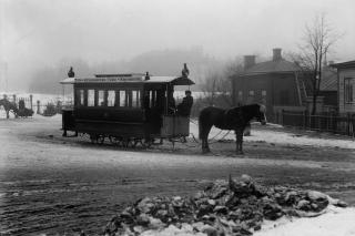 Hästspårvagn på vintern. I bakgrunden hus i dimma.