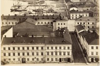 Vanha mustavalkoinen kuva jossa näkyy Helsinkiä 1800-luvun lopun asussa. Etualalla Senaatintori