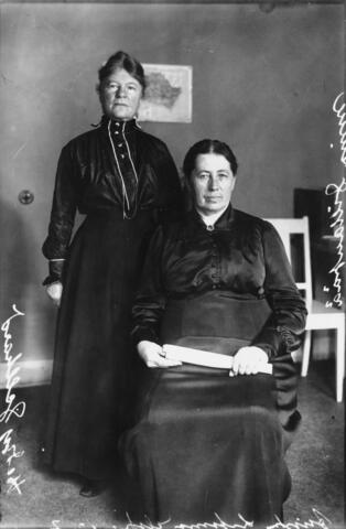 Vassemmalla seisoo Hedvig Gebhard, oikealla istuu Miina Sillanpää