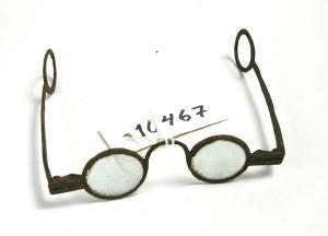 Silmälasit, joiden rautaiset kehykset ja sangat ovat ruostuneet. Linssit ovat pyöreät ja pienehköt. Aisoja ei ole muotoiltu korvan taakse sopimaan vaan ne päättyvät pyöreään silmukkaan. 