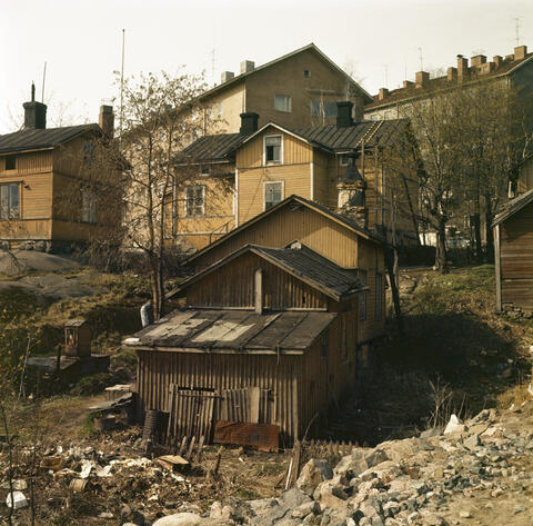 Hermannin kortteli 657. Oihonnankatu 20. Pihalla on kaivo ja jätteitä (komposti?). Taustalla oleva kerrostalo on Helmikatua.