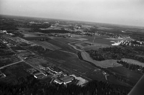 Viistoilmakuva pienlentokoneesta Marttilan pientaloalueen pohjoispuolelta pohjoisen suuntaan. Etualalla Päiväläisentien rakennuksia. Vasemmalla Muonamiehentie ja Ristipellontie sekä Vihdintie. Taustalla Malminkartanon ja Lassilan peltomaisemia, keskellä Mätäjoki. Oikealla Kannelmäki.