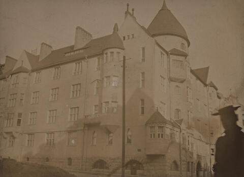 Vuonna 1902 valmistunut asunto-osakeyhtiö Olofsborg (arkkitehdit Geselius, Lindgren, Saarinen) Katajanokalla. Kuvan oikeassa reunassa on hattupäinen nainen.