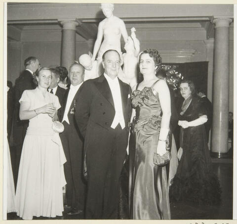 Iltapukuisia ihmisiä Presidentinlinnassa. Taustalla marmoriveistos.