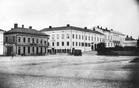 Etualalla on tyhjää mukulakivitoria, taustalla on Eteläesplanadin alkupään 2- tai 3-kerroksiset rakennukset. Ihmisiä ja hevosvaunujakin näkyy.