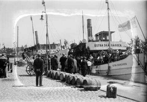 Människor på väg bort från stan för att fira midsommar på 1920-talet.  Två ångfartyg vid kajen i Södra hamnen.