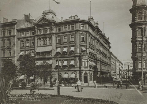 Hotell Kämp, Norra Esplanaden 29. Till höger Glogatan. Framför hotellet syns hästdragna vagnar, på Esplanaden syns människor.