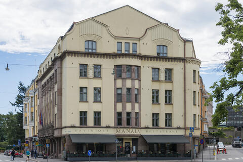 Ostrobotnian talon julkisivu kuvattuna Dagmarinkadun puolelta. Julkisivussa lukee RAVINTOLA MANALA RESTAURANT, ja oven kummallakin puolella on terassi.