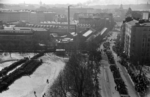 Ilmakuvassa on valtavasti ihmisiä kokoontuneena nykyiselle Väinö Tannerin kentälle ja marssimassa Hämeentiellä. 