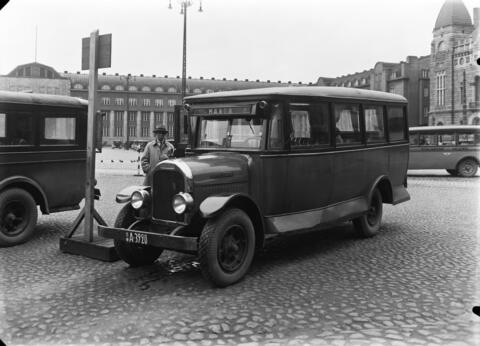 På Järnvägstorget står en buss som man numera skulle kalla minibuss. Bakom den syns en flygel till järnvägsstationen samt Nationalteatern.