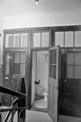 En trappavsats med en gemensam toalett vars dörr står öppen.