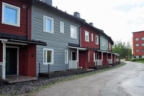 Hirsistä rakennettuja kaksikerroksisia rivitaloasuntoja. Joka toinen on punainen ja joka toinen siniharmaa. 