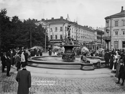 Havis Amanda -suihkukaivo Kauppatorilla paljastustilaisuuden jälkeen. Taustalla Pohjoinen Esplanaadikatu (Pohjoisesplanadi) 19 - Unioninkatu 28.