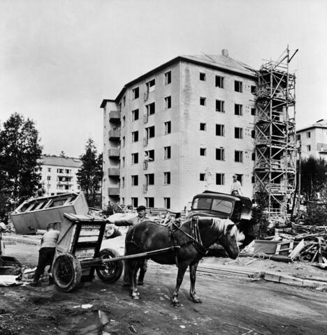 Asuinkerrostalon rakennustyömaa osoitteessa Pietari Hannikaisen tie 8 - Näyttelijäntie 4 Pohjois-Haagassa. Kuva on otettu kaakosta, oikealla asuinkerrostalo Näyttelijäntie 6 ja vasemmalla taustalla Näyttelijäntie 3. Etualalla hevoskärryt ja työmies.
