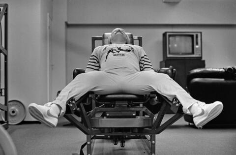 Mies harjoittaa jalkalihaksiaan kuntosalilaitteen avulla.