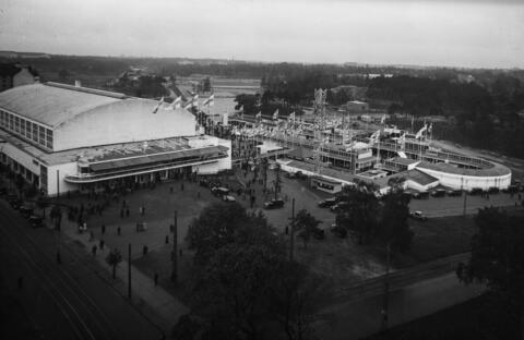 Suurmessut 1935 Helsingin messuhallissa. Yleisnäkymä messualueelle ja messuhalliin, jonka päälle on satanut hento lokakuinen lumisade. Taustalla äärimmäisenä vasemmalla 1930 toimintansa aloittanut Helsingin tuberkuloosisairaala eli Laakson sairaala. Kuvan keskiosassa metsän keskeltä erottuu nykyisin Auroran sairaalana tunnettu lastensairaala, joka perustettiin vuonna 1914 Helsingin kunnalliseksi kulkutautisairaalaksi. Sen ja messuhallin välissä oleva tasoitettu alue on tulevan Helsingin Olympiastadionin rak