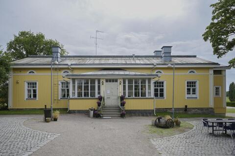 Keltaiseksi maalattu yksikerroksinen kartanon päärakennus.