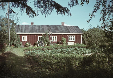 Punamullattu harjakattoinen yksikerroksinen rakennus, jossa moniruutuiset ikkunat.
