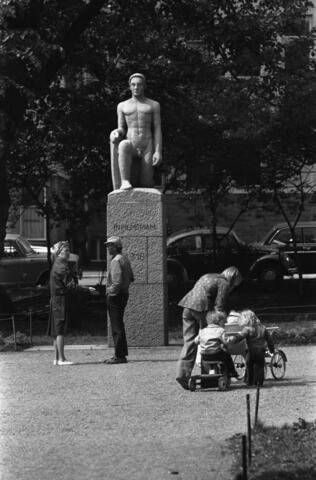 Ovanpå en minnessten en skulptur av en knäböjande man