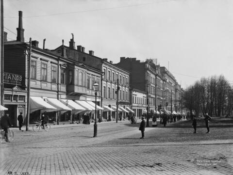 Pohjoinen Esplanaadikatu (Pohjoisesplanadi) 41, 39, 37, 35. Kaksi- tai kolmekerroksisia puurakennuksia, jalankulkijoita ja pyöräilijöitä, kaasulyhty.